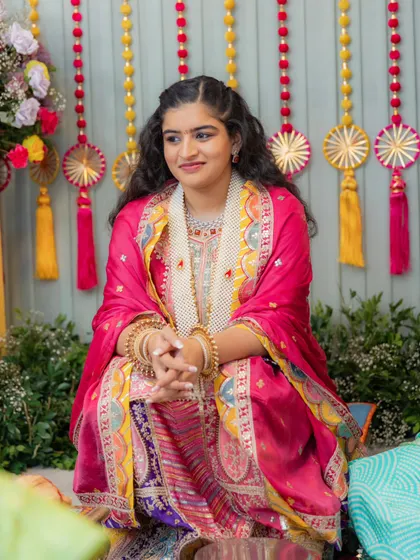 The bride during her Bane Bithai ceremony. For this traditional event, we chose a heavily embroidered pink and purple suit with beautiful gota patti work, paired with floral jewelry.
