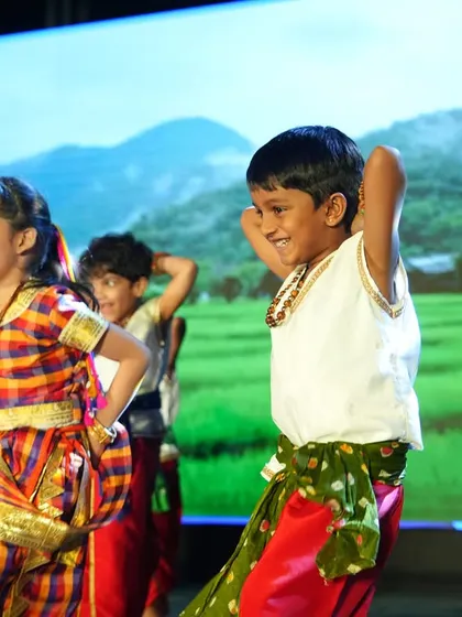 Blossoming minds, shining stars. Children in colorful folk costumes perform a dance on stage for our Annual Day.