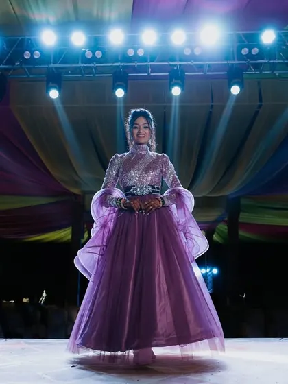 A stunning solo portrait of the bride on the Sangeet stage, illuminated by spotlights.