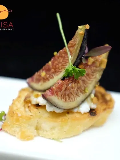 A perfect pairing of sweet and savory. This canapé features fresh fig and creamy ricotta on a toasted crostini, finished with a sprinkle of pistachios for a delightful texture.