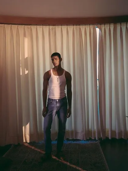 A wide shot for an Amama Jewels campaign, featured on PhotoVogue. The image uses natural light filtering through curtains to create a soft, cinematic mood.