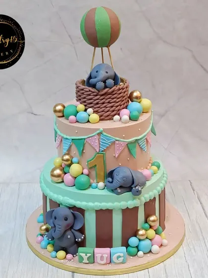 An adorable 3kg three-tier mixed fruit cake with an elephant and hot air balloon theme. The cake is decorated in soft pastel colors.