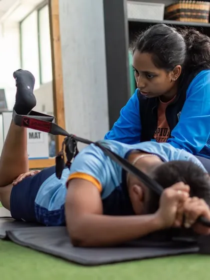 A physiotherapist assists an athlete with a hamstring stretch. Rehab is not about rest, it's about smart adaptations to rebuild strength, stability, and mobility.