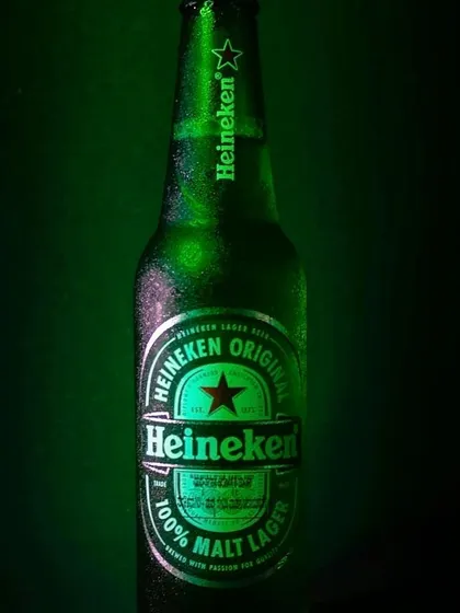 A crisp, clear shot of a Heineken bottle, with condensation droplets catching the light. This photo emphasizes the cold and refreshing quality of the beverage.