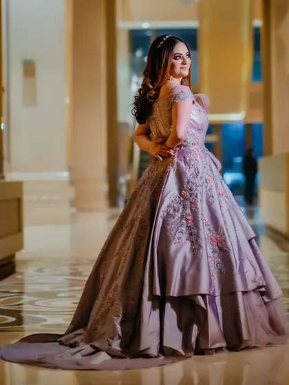 A portrait of the bride in her lavender gown, showcasing the dress's intricate embroidery and layered design. The elegant hotel lobby provides a sophisticated backdrop.