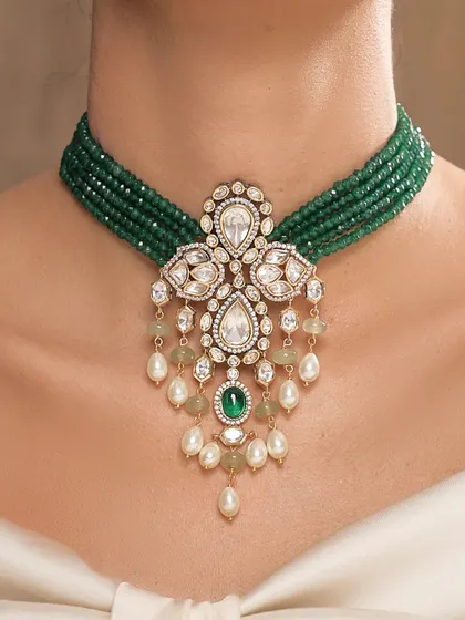 An elegant choker made of emerald beads, featuring a central polki and pearl pendant that adds a touch of classic glamour.