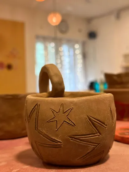 A raw, hand-built mug with a star pattern carved into it. This piece is full of rustic charm.