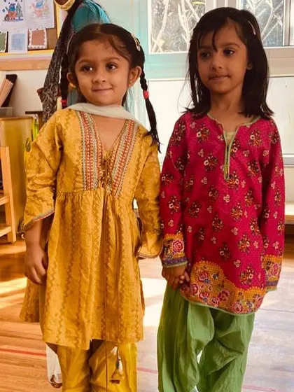 Two friends holding hands, dressed in their festive best for our cultural celebrations. These moments build strong bonds and a sense of community.
