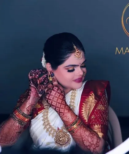 A beautiful Brahmin bride framed by the ring light. Her look features defined eyes and is paired with a traditional white and red nine-yard saree and intricate henna.