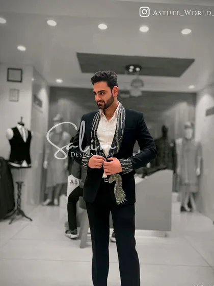 A client in a black suit with a unique scarf-like embroidered lapel. This is a fashion-forward design that blends accessories and the garment into one.