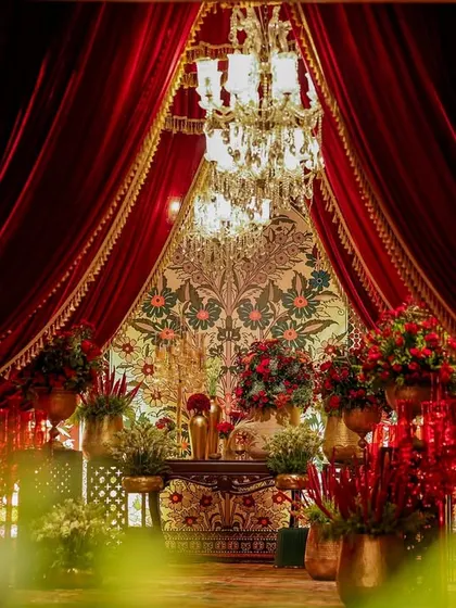 A beautifully framed view of an opulent floral display, seen through an entryway draped in red velvet. This composition creates a sense of discovery and theatrical reveal.
