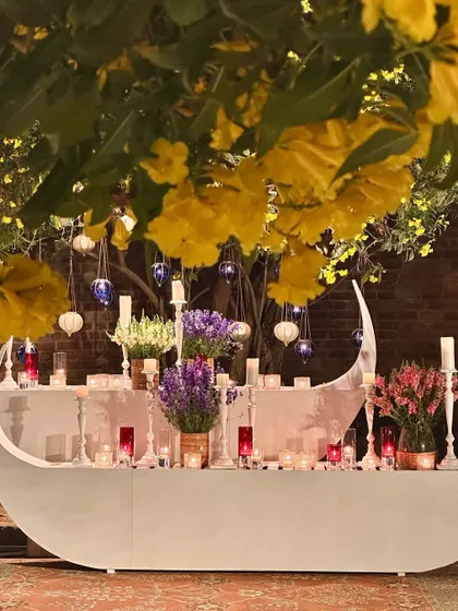 A close-up of the boat-shaped table, decorated with yellow flowers, purple blooms, and candles.