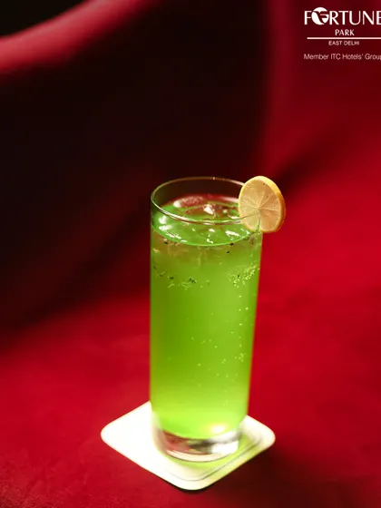 A vibrant green mocktail, served against a rich red backdrop, showcasing the bold colors and refreshing flavors of our non-alcoholic beverage selection.