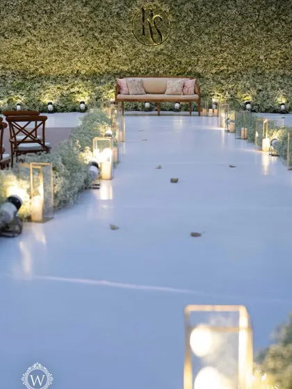 An ethereal all-white reception. The aisle and backdrop are adorned with clouds of baby's breath, while flickering candles cast a warm, romantic glow, creating a scene straight out of a fairy tale.
