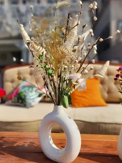 A modern and minimalist centerpiece featuring dried flowers and grasses in a stylish white ceramic vase.