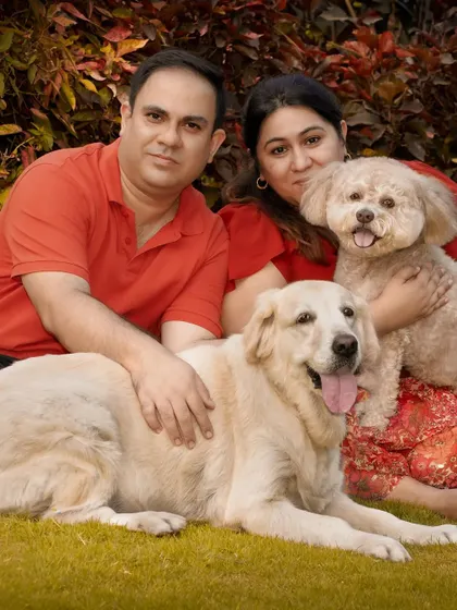 The complete family, smiling together in a beautiful garden setting.