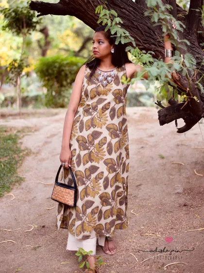 Showcasing a sleeveless leaf-print kurta, this photo captures a perfect summer look. The addition of the handbag as an accessory helps customers visualize how to style the piece, making it more relatable and commercially appealing.