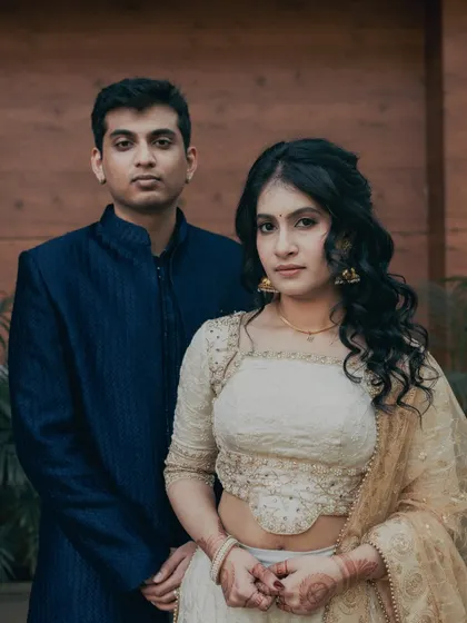 A classic couple portrait. Her makeup is fresh and radiant, with soft curls framing her face, creating a perfect look for an engagement ceremony.