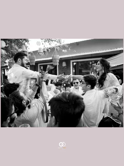 A black and white shot of the couple being lifted up by their friends during a joyous and energetic Haldi celebration.
