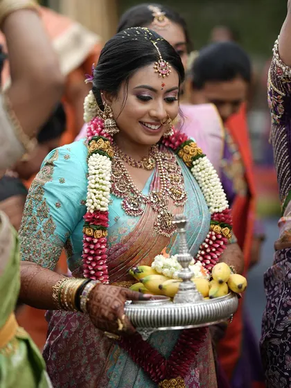 A candid shot of our client Nidhi during a wedding ceremony. Adorned with a flower garland, her custom-embroidered temple blouse shines, showcasing how tradition meets elegance in our designs.