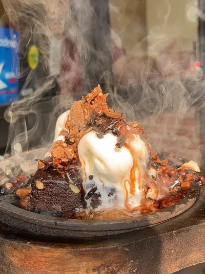 A dramatic shot of my Sizzling Brownie, with steam rising as the hot chocolate sauce hits the sizzler plate.