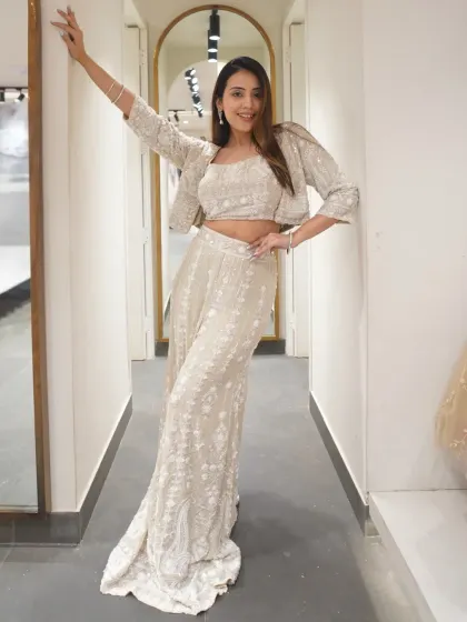 A little bit of desi, a little bit of drama. This off-white embroidered palazzo set with a crop top and jacket is perfect for a modern festive look.