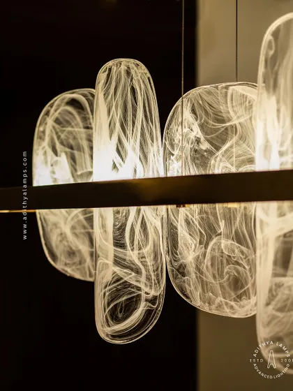 This linear pendant features organic, rounded glass elements with a beautiful white smoke effect inside. Suspended from a simple gold bar, it provides a soft, ethereal glow, ideal for creating a serene atmosphere over a dining table.