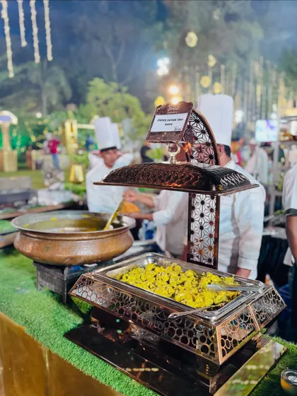 A serving of freshly cooked Chicken Zafrani Tikka Barra in an ornate chafing dish, ready to be served.