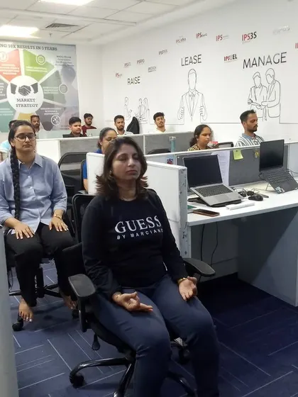 Employees at IPS Group in Goregaon practice seated meditation at their desks. This demonstrates how easily yoga and mindfulness can be integrated into the corporate setting without disrupting the workspace.