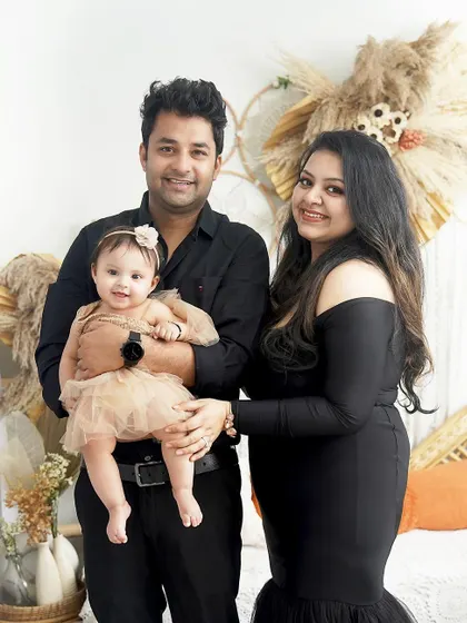 A classic family portrait with warm smiles. The coordinated black outfits and the baby's sweet expression make this a timeless keepsake.