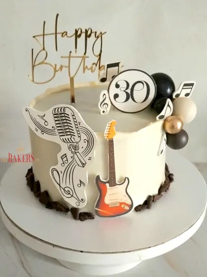 A cool music and guitar theme cake for a 30th birthday. This no-fondant cake is decorated with edible music notes, a guitar, and a vintage microphone, making it a great choice for any music enthusiast.