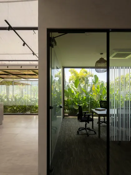 Glass-walled meeting rooms look out onto the surrounding greenery, bringing nature into the workspace.