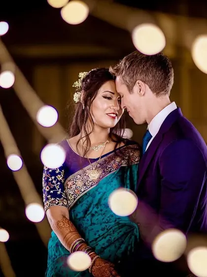 A romantic portrait of the couple surrounded by bokeh lights. The warm glow creates a magical and intimate atmosphere for this reception shot.
