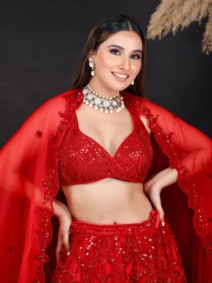 A vibrant shot of a model in a modern red sequined lehenga with a cape. This image is perfect for showcasing contemporary bridal or sangeet outfits.