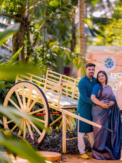A lovely portrait of a couple by a traditional Indian cart. Their coordinated blue outfits look beautiful in the lush, green setting.