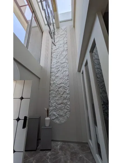 An interior detail from a bungalow in Lonavala, showing a textured feature wall in a double-height space, captured during a site visit.