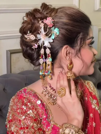 A side view of an elegant bridal updo, featuring a unique, dangling hair accessory and perfectly blended makeup.