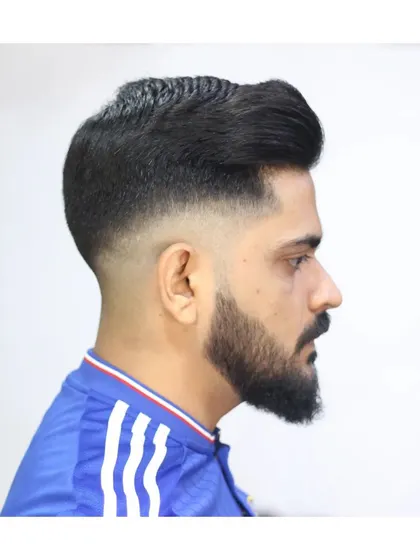 A high-volume pompadour paired with a clean skin fade and a sharp beard lineup. This style combines classic height with modern fading techniques.