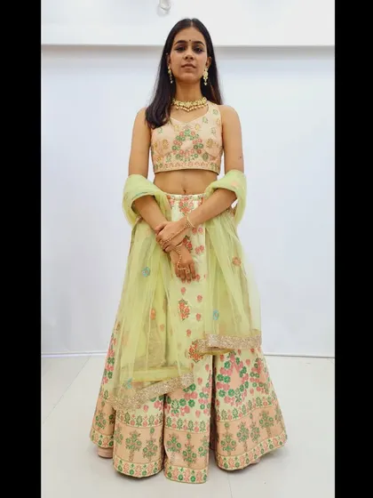 A full frontal view of the pastel green floral embroidered lehenga, showing the sleeveless blouse and the light net dupatta.