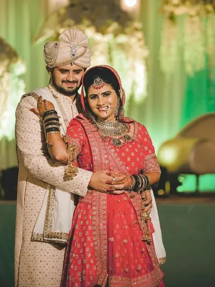This couple chose a beautiful red lehenga paired with a cream sherwani. The black bangles on the bride add a unique touch, showing how our rental outfits can be personalized with your own accessories.