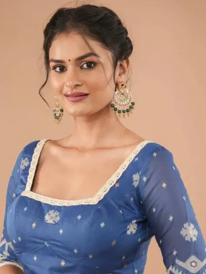 A model wears a blue Jamdani cotton blouse with lace trim, accessorized with large, ornate chandbali earrings.