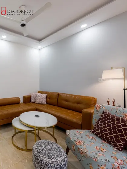 This living room combines a comfortable tan leather sofa with a floral accent chair for a touch of eclectic style. The space feels warm and inviting, perfect for relaxing with family.