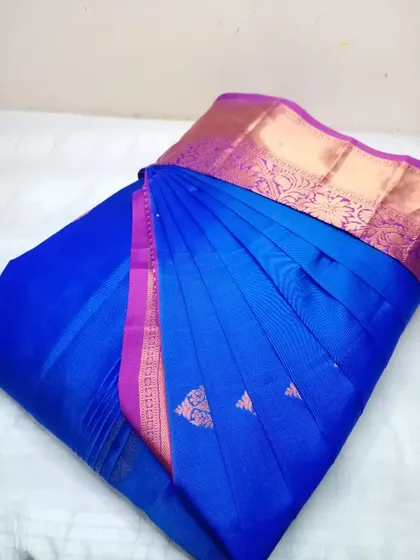 A vibrant royal blue saree with a pink border. The pleats are set, and the saree is ready to be draped in under five minutes.