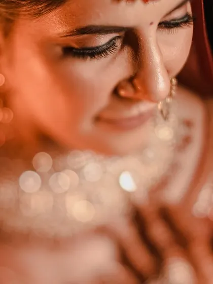 A beautiful, artistic close-up of the bride looking down. The soft focus and warm lighting create a dreamy, bokeh effect, highlighting her serene expression.