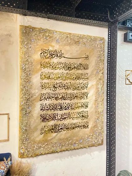 A large Ayat al-Kursi artwork with a beige marble effect, installed on a textured wall in a client's space.
