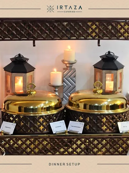 A classic dinner setup with two golden chafing dishes framed by candle-lit lanterns. This timeless arrangement is perfect for formal dinners and traditional celebrations.