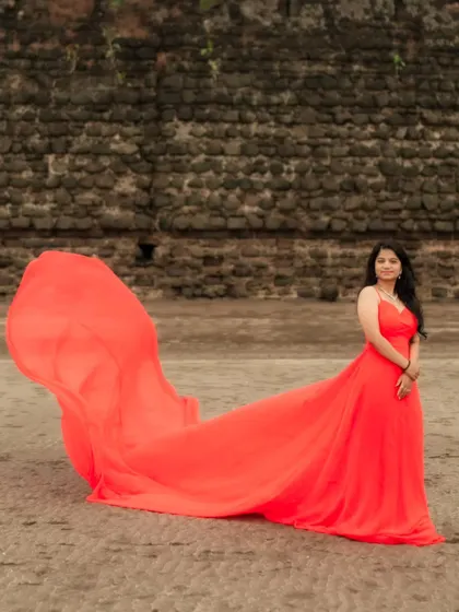 A solo moment of beauty on the beach. The vibrant red trail gown spreads out on the sand, creating a stunning and powerful image.