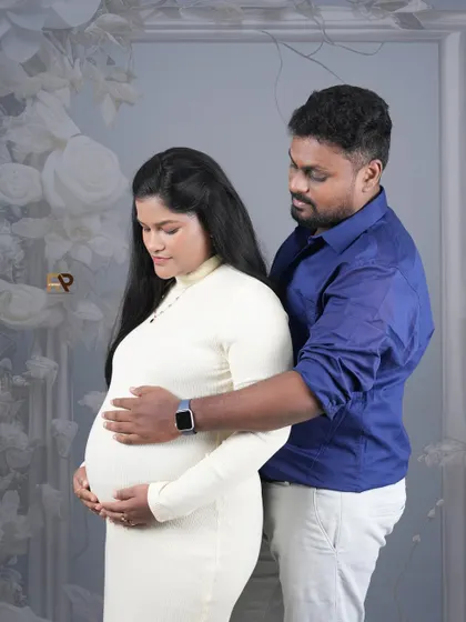 A beautiful portrait of a couple in a modern studio setting. The dad-to-be's hands gently rest on the baby bump, a classic pose that is always full of emotion.