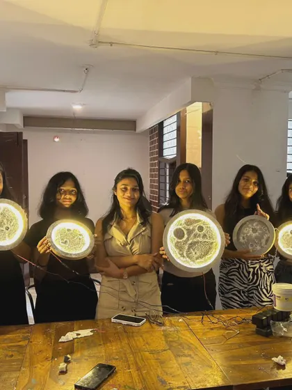 A group of proud students showing off the glowing moon lamps they created during a school workshop event at our cafe.