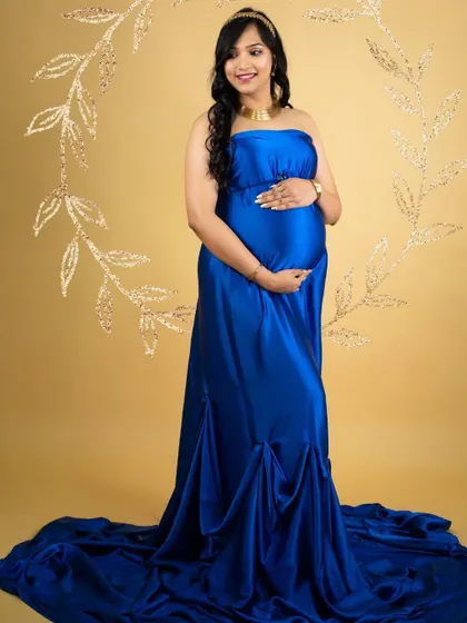 A classic and elegant portrait in a royal blue satin gown. The simple gold background and floral wreath prop add a touch of sophistication.